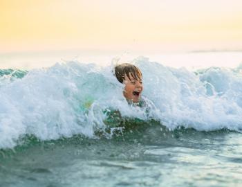 little boy laying in the waves