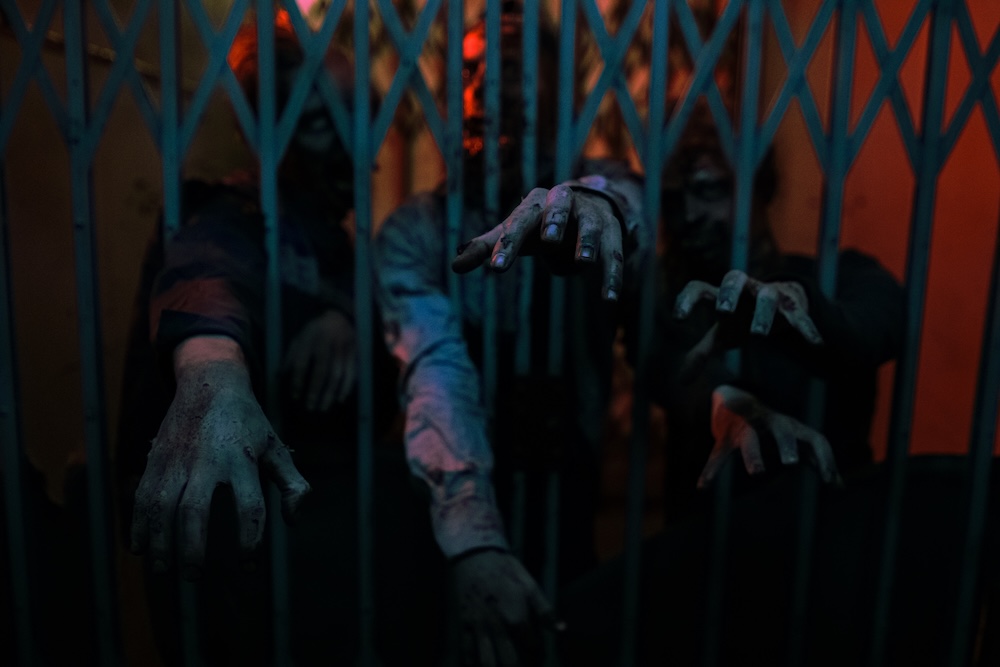 Creepy hands reaching through a gated corridor in a haunted house