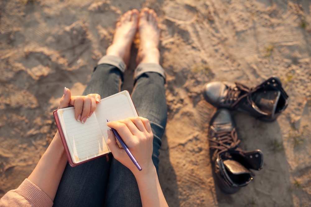 woman journaling on the beach